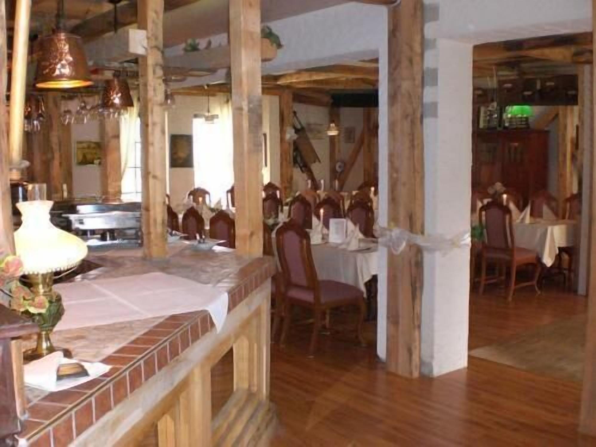 A dining area with wooden beams, a brick accent wall, and hanging pendant lights.