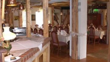 A dining area with wooden beams, a brick accent wall, and hanging pendant lights.