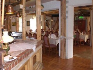A dining area with wooden beams, a brick accent wall, and hanging pendant lights.