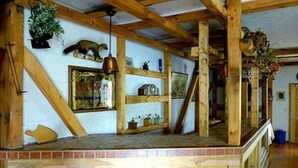 Un interno rustico con travi in legno, un camino in mattoni e scaffali con diversi oggetti.