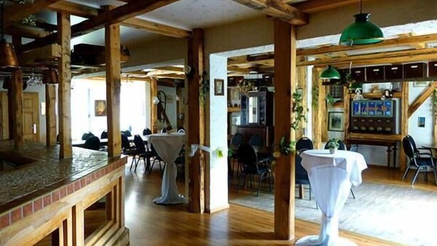Arredamento rustico con travi in legno, un'area bar e tavoli apparecchiati per la cena.