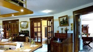 Una stanza spaziosa con un tavolo rotondo grande, armadietti in legno e un quadro appeso al muro.