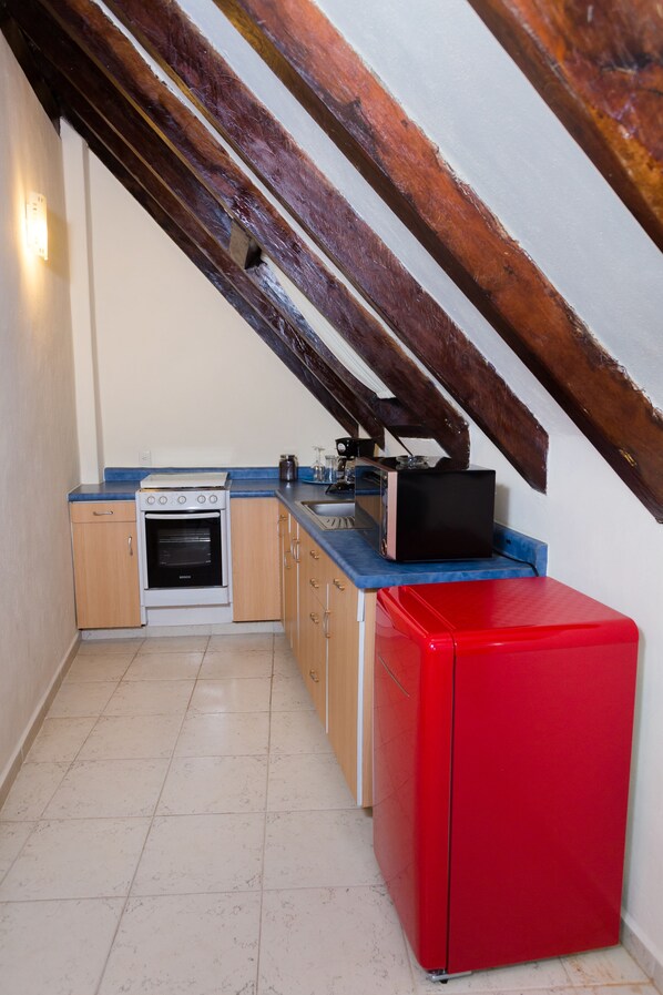 A compact kitchen with a built-in oven, a microwave, and a red refrigerator. - Hotel La Joya (Isla Mujeres)