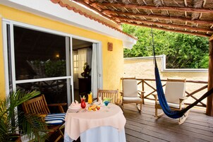 A wooden deck with a table set for dining, a hammock, and outdoor seating.