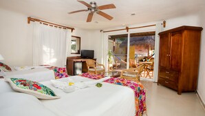 Habitación de hotel con cama, escritorio con computadora, armario y balcón con vista a la playa.