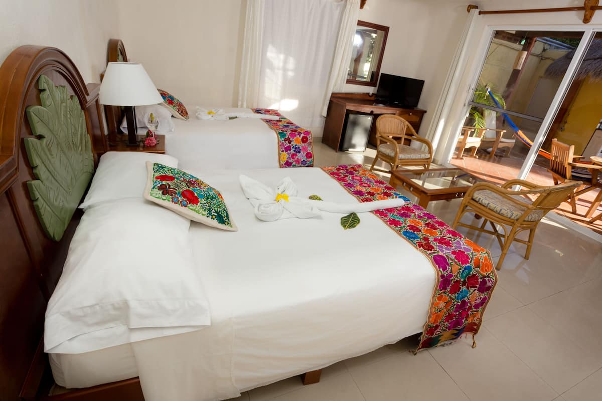 A hotel room with two beds, a desk, a chair, and a TV.