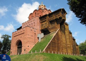 A large, historic building with a prominent red brick facade and a wooden structure attached to it.
