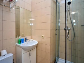 A bathroom with a sink, mirror, and shower.