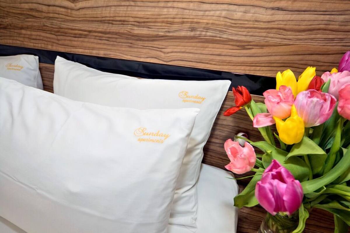 A bed with white pillows and a bouquet of tulips.