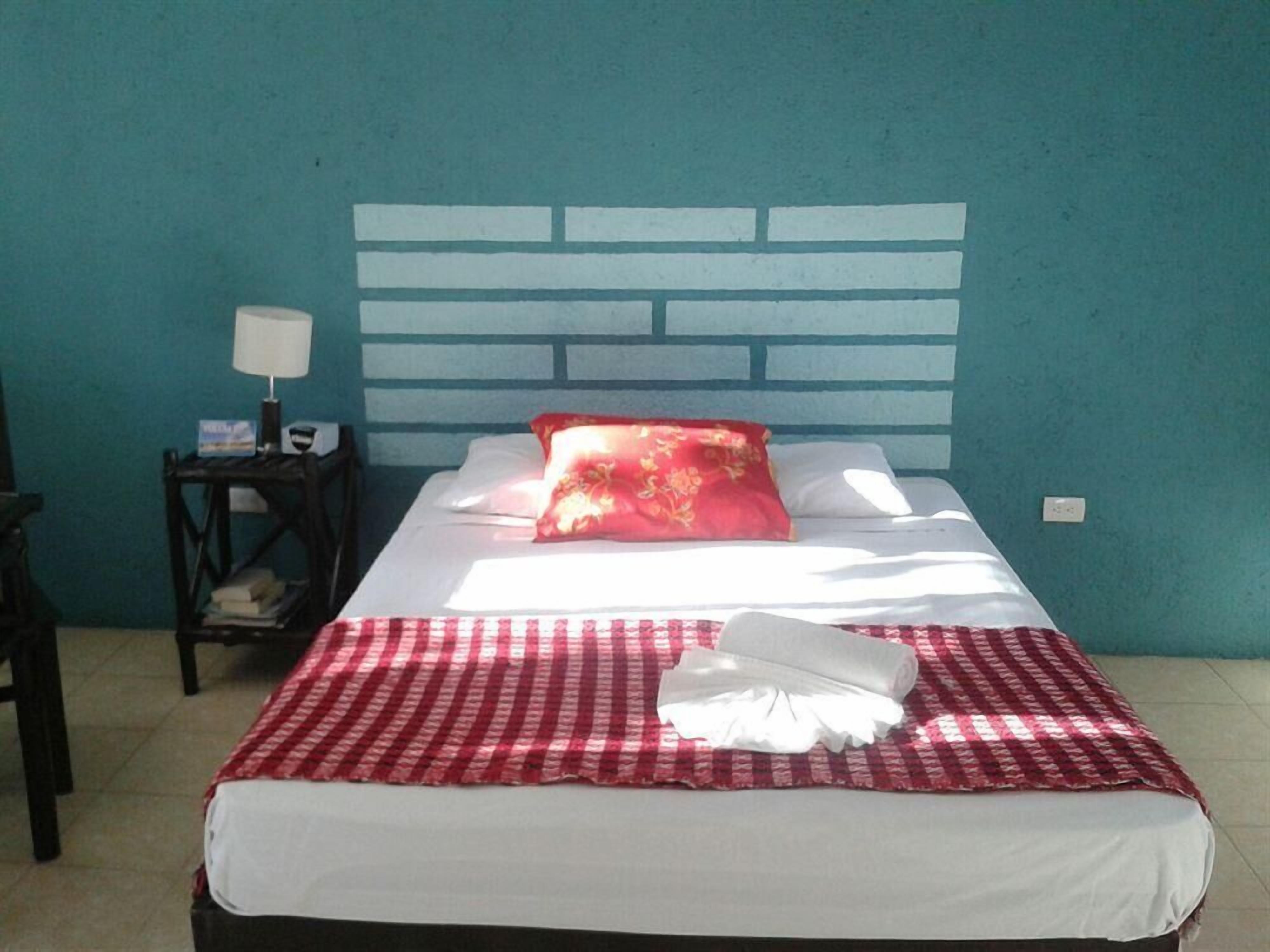 A hotel room with a bed, a nightstand, and a wall with a brick pattern.