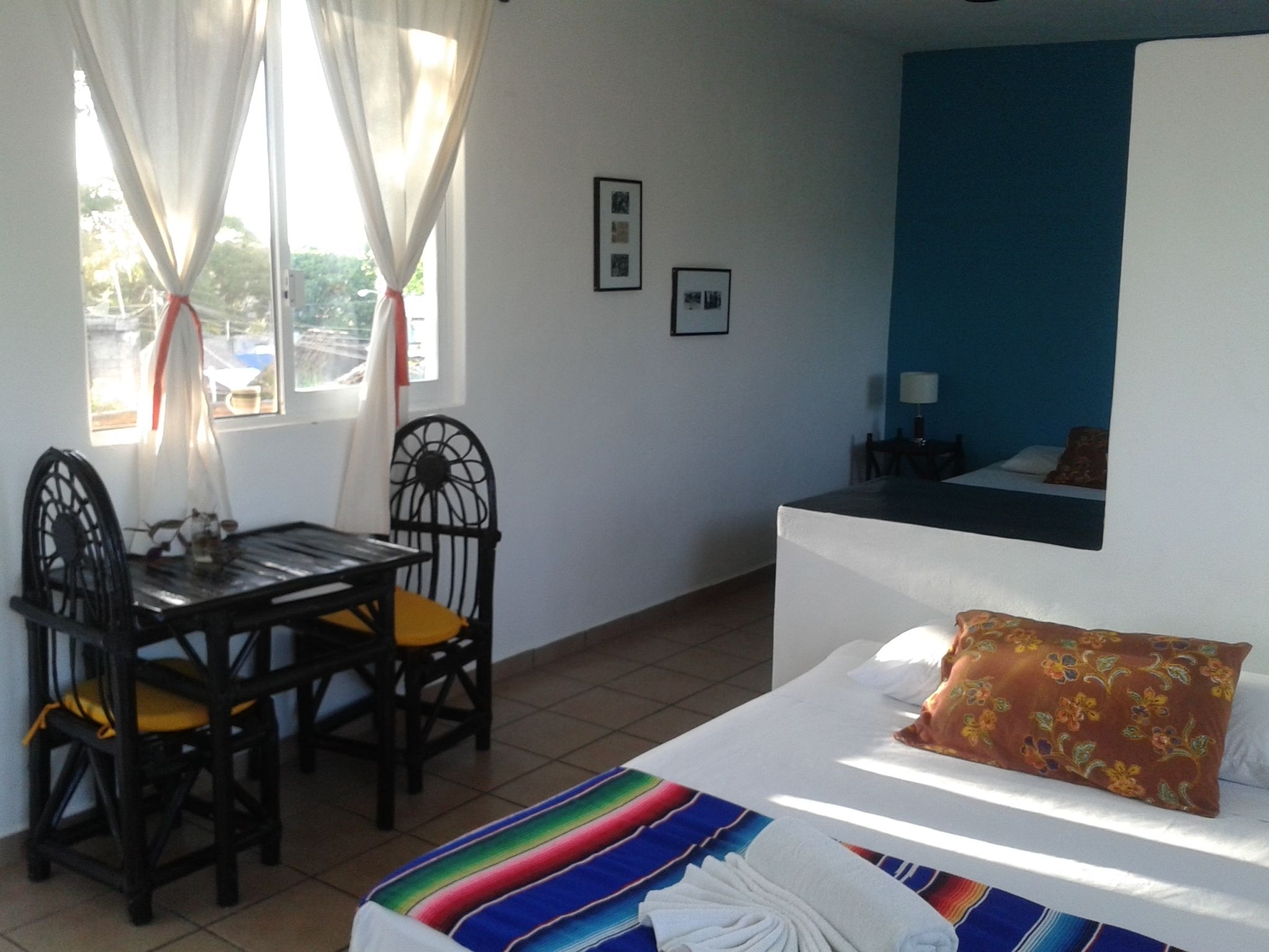 Una habitación de hotel con cama, una mesita con sillas y una ventana con cortinas.