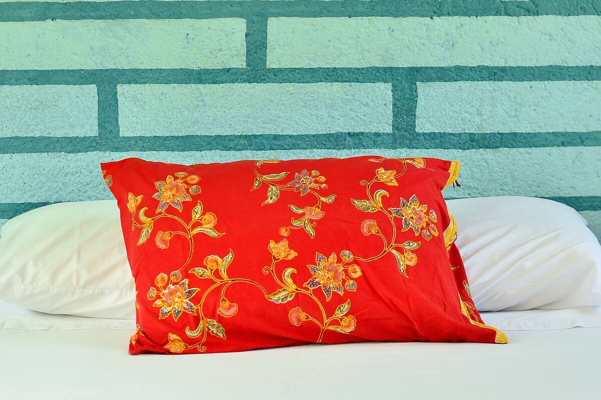 A bed with a red pillow and a striped blanket.