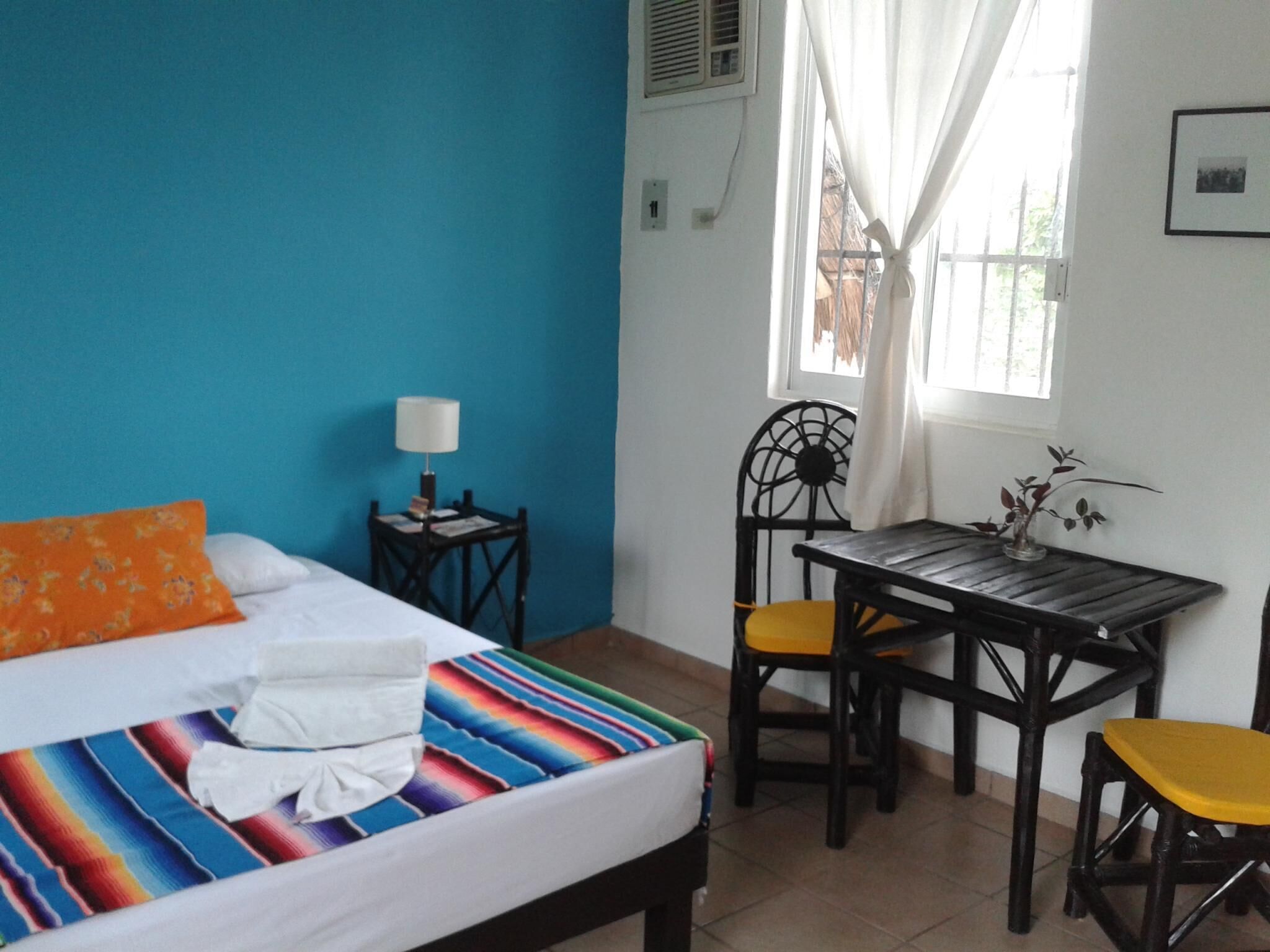 A room with a bed, a small table, a chair, and a window with curtains.