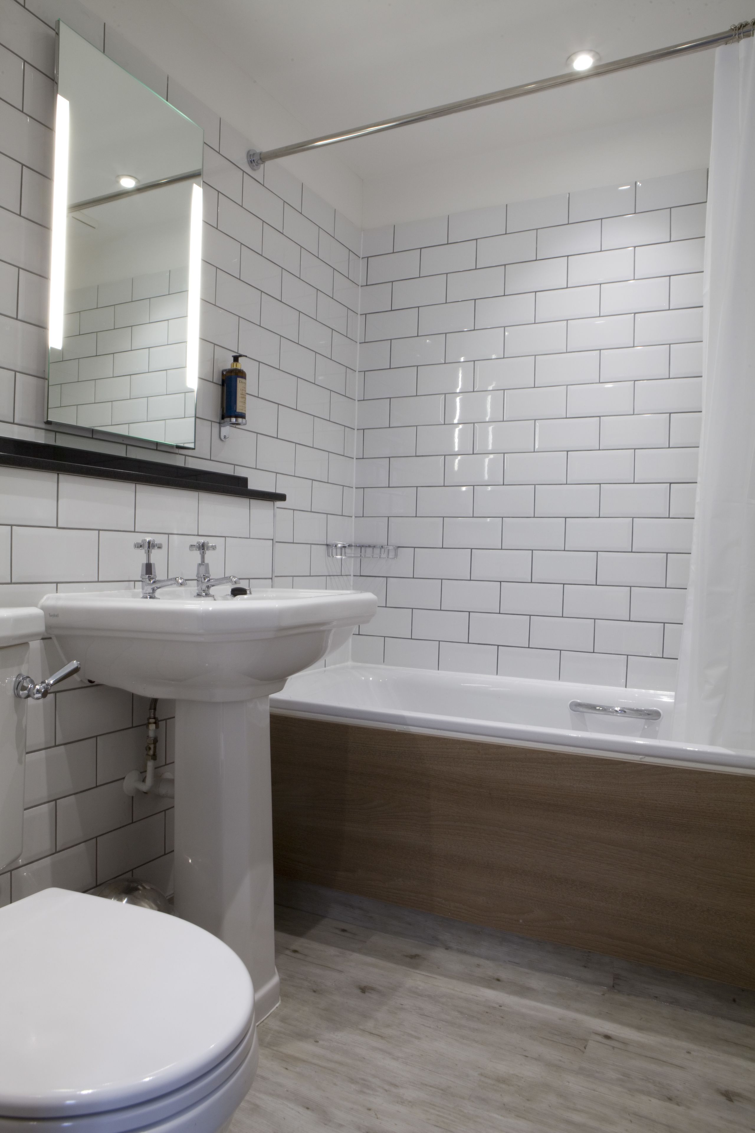 A bathroom with white tiled walls, a white sink, a toilet, and a bathtub.