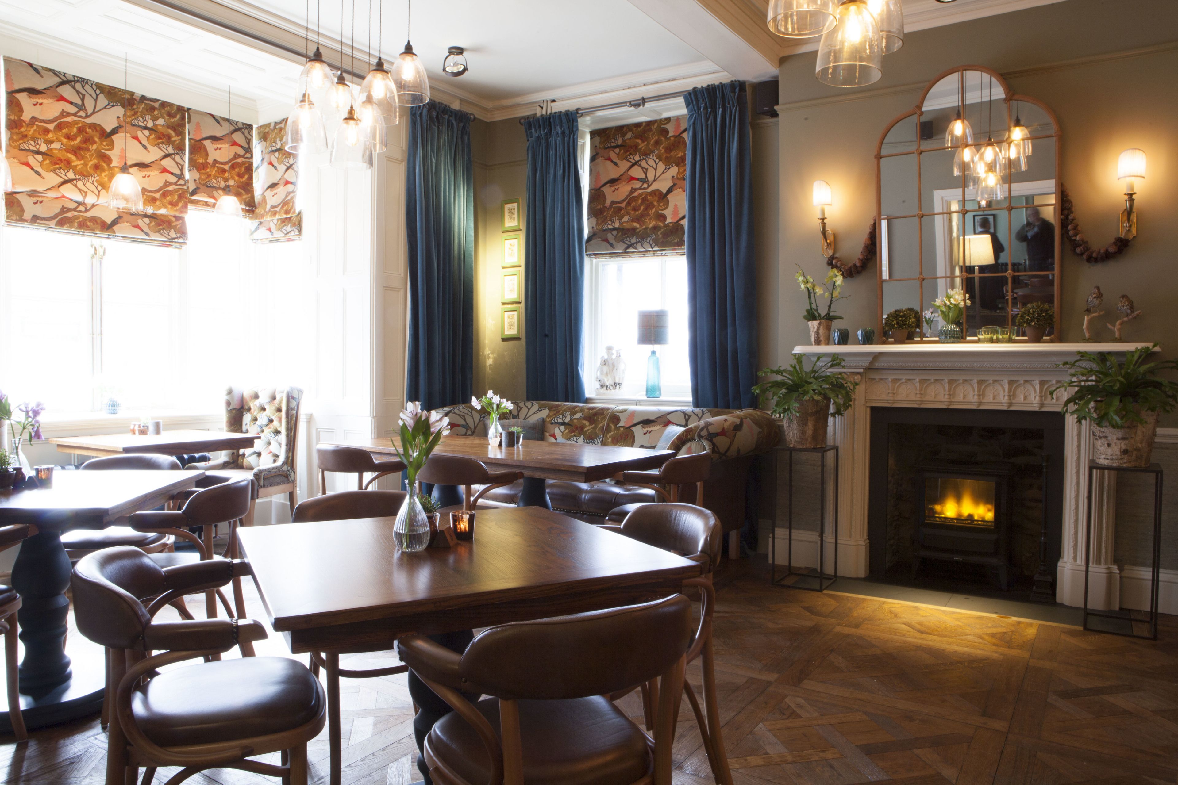 A dining area with wooden tables and chairs, a fireplace, and decorative wall art.