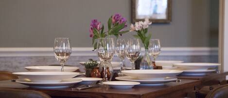 A dining table set with plates, glasses, and vases of flowers.