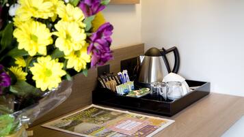 Una reception hotel con un giornale, un vassoio con tazze da caffè, un bollitore e un vaso di fiori.