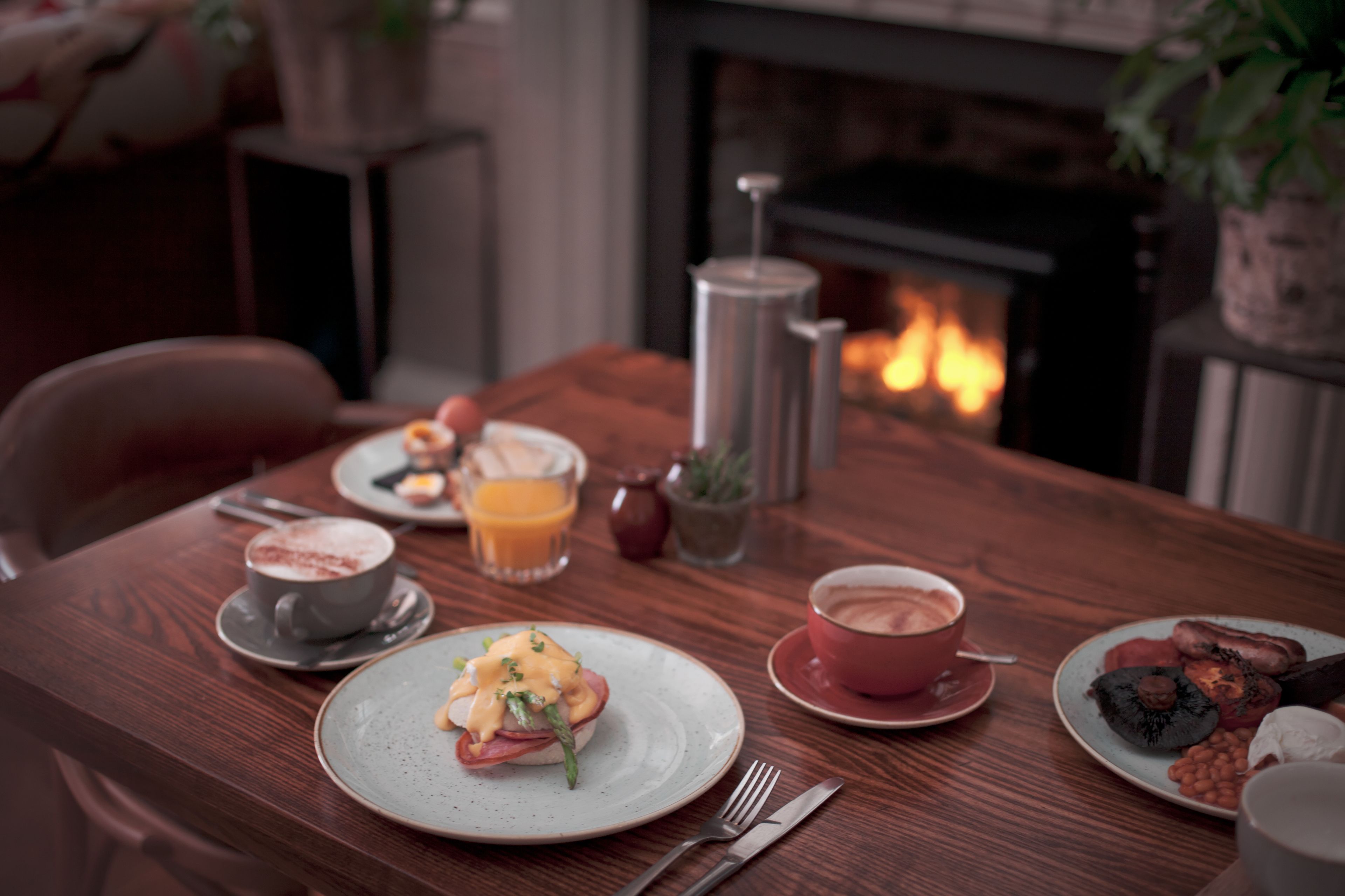 A dining table with plates of food, a coffee cup, and a teapot.