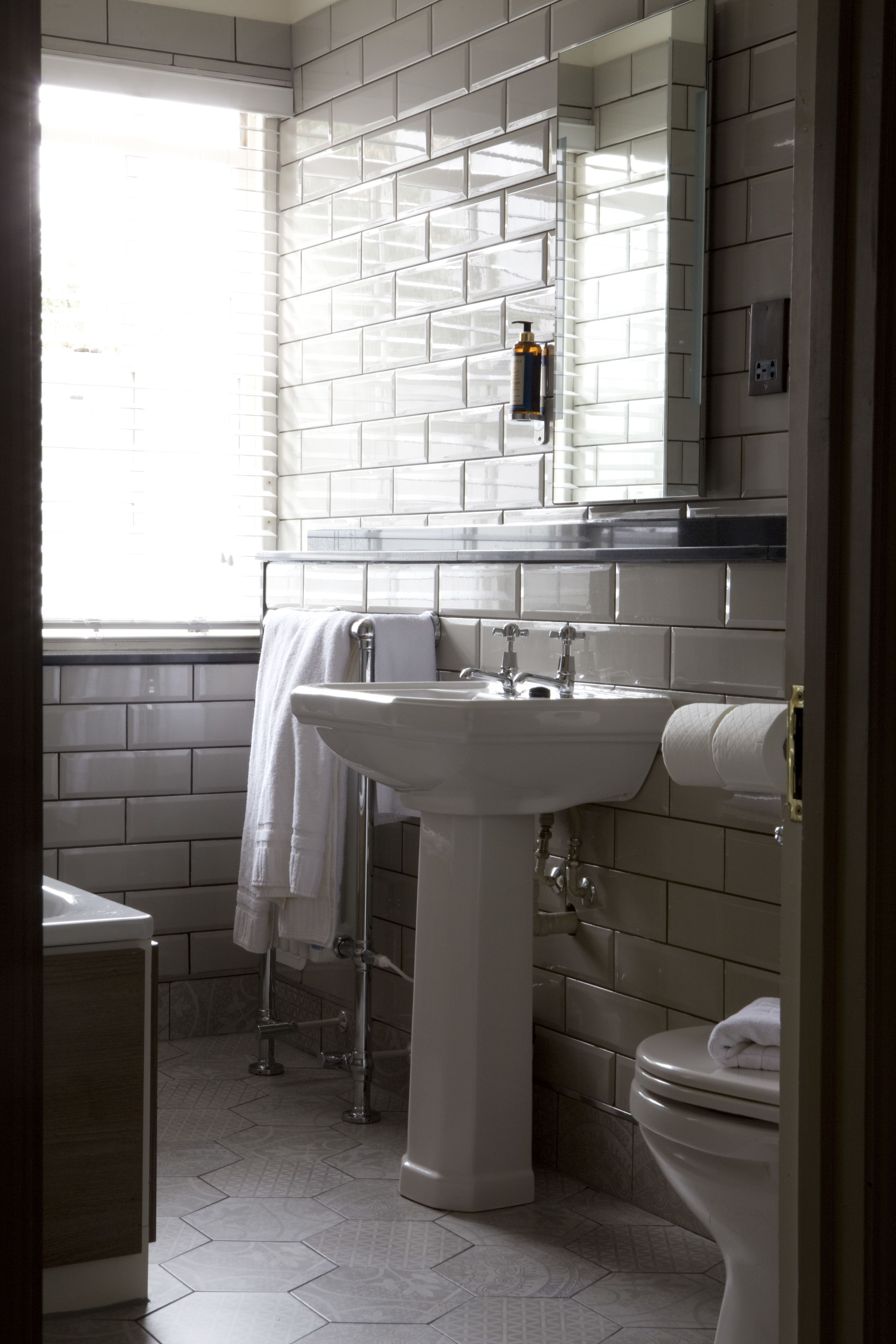 A bathroom with a white sink, toilet, and window.
