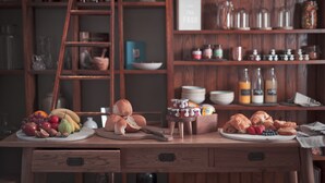 A wooden table with bread, fruits, and pastries.