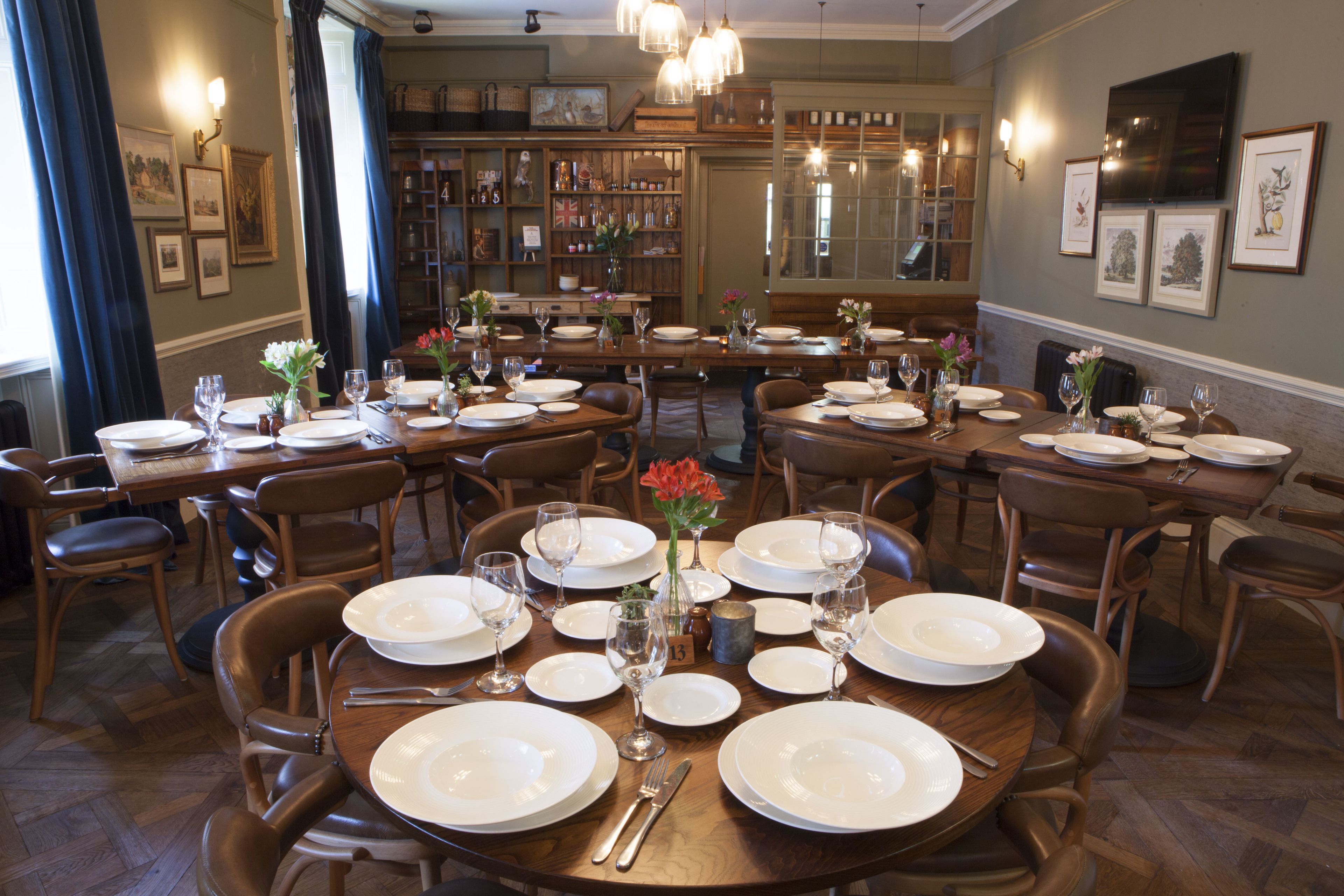 Un espace repas avec plusieurs tables rondes dressées pour le repas, chacune agrémentée d’assiettes blanches, de verres et de couverts.