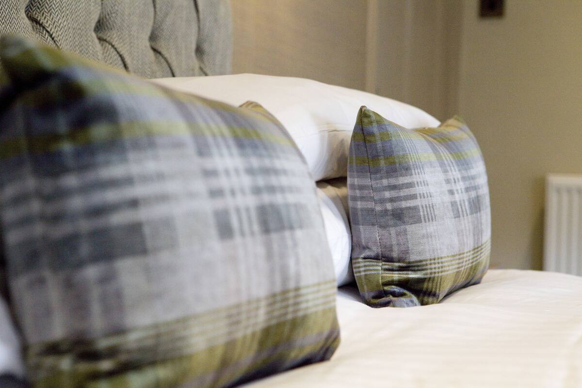 A bed with a white mattress and multiple pillows in plaid patterns.
