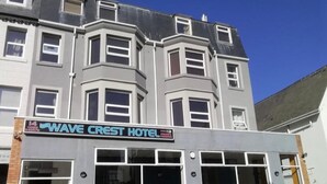 Exterior del Hotel Wave Crest con un diseño moderno, que cuenta con grandes ventanales y una entrada destacada.