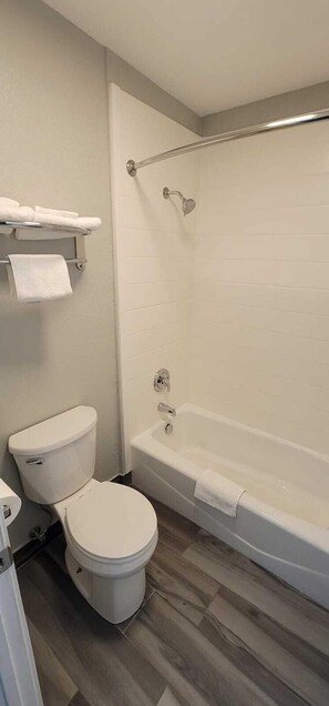 A bathroom with a toilet, bathtub, and a shower curtain rod.