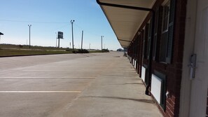 A long, covered walkway leading to a building with multiple windows and a brick facade.