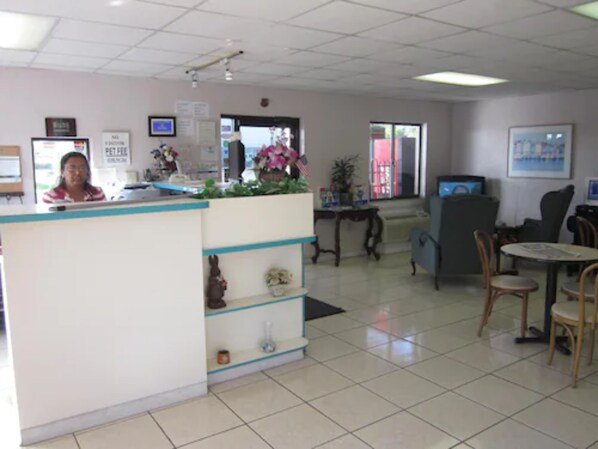 A reception area with a counter, a computer, and a seating area with chairs and a table.