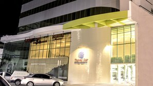 A modern hotel building with a curved facade, large windows, and a visible Travel Inn sign. - Green Hotel Cabo Frio (Cabo Frio)