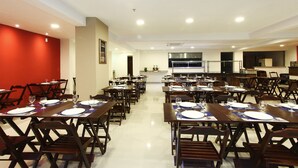 A conference room with multiple tables set for dining, equipped with chairs and table settings. - Green Hotel Cabo Frio (Cabo Frio)