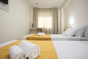 A hotel room with two beds, a small table with a yellow tablecloth, and a chair. - Green Hotel Cabo Frio (Cabo Frio)