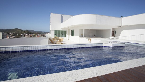 A modern building with a swimming pool, a covered outdoor area, and a view of the surrounding landscape. - Green Hotel Cabo Frio (Cabo Frio)