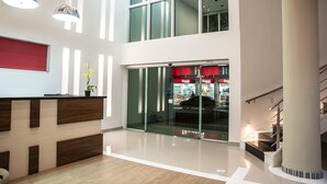 A modern lobby with a reception desk, glass doors, and a staircase. - Green Hotel Cabo Frio (Cabo Frio)