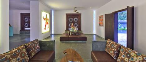 Un vestíbulo moderno con una zona de estar central, una mesa de centro de madera y un libro, y obras de arte en las paredes.