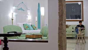 A room with a bed, a sofa, a small table, and a chair. There is a large window and a framed picture on the wall. - Purity at Lake Vembanad (Cherthala)