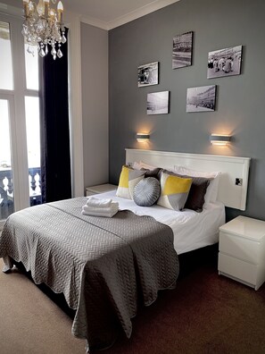 A neatly arranged bedroom with a large bed, bedside tables, and wall-mounted light fixtures. - Lansdowne Hotel (Hastings)