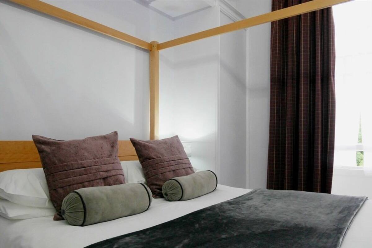 A neatly made bed with a wooden headboard, two pillows, and a grey blanket.