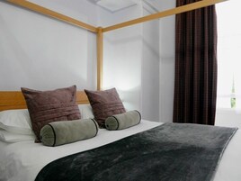 A neatly made bed with a wooden headboard, two pillows, and a grey blanket.