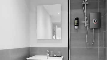 A modern bathroom with a white sink, a mirror, and a shower with a handheld showerhead and a wall-mounted control panel.