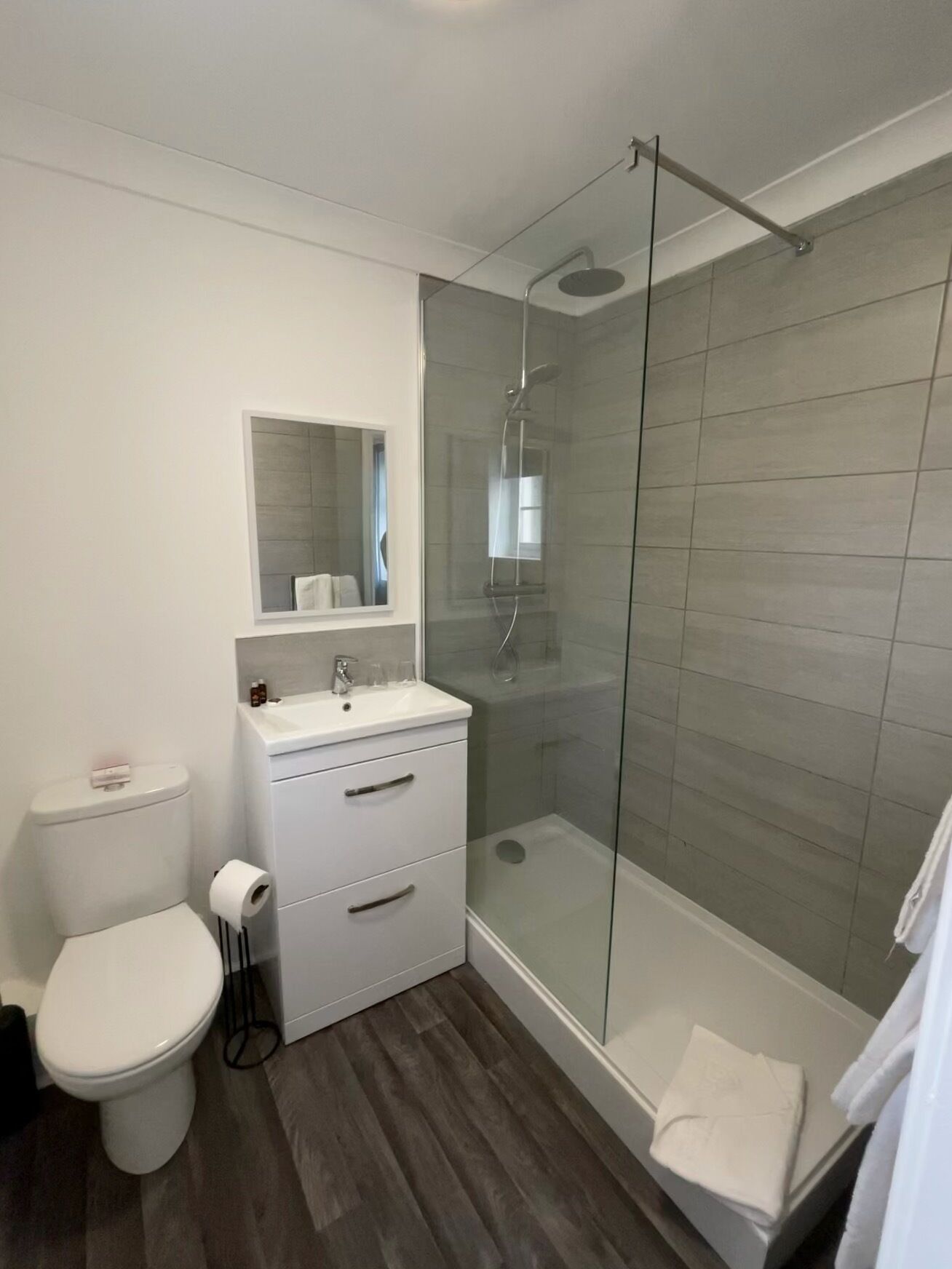 Une salle de bain moderne avec une douche à parois de verre, un lavabo blanc et des toilettes.