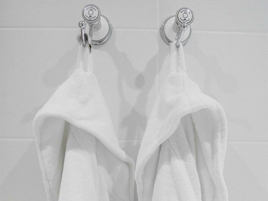 Deux serviettes blanches sont suspendues à un porte-serviettes fixé au mur.