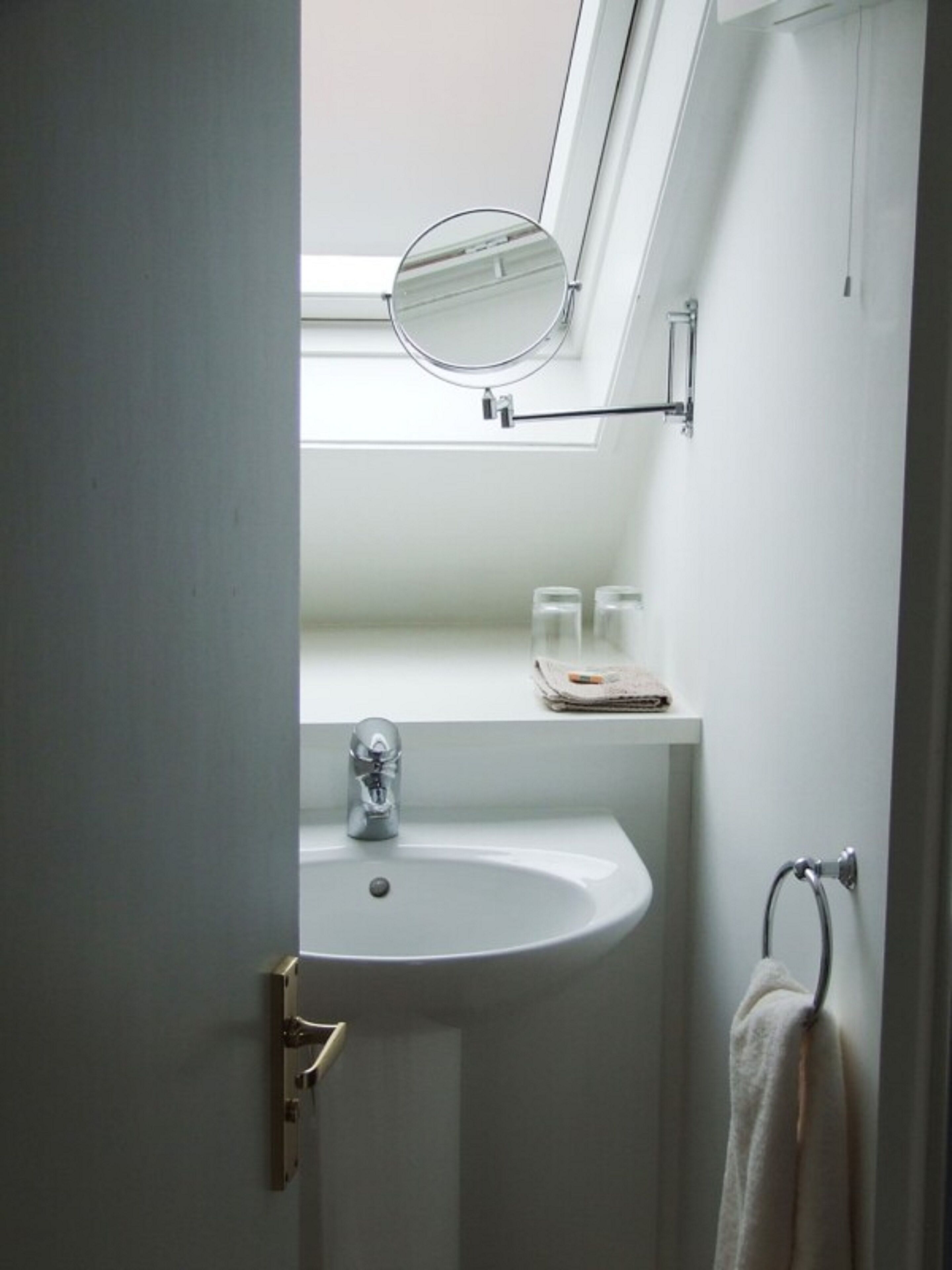 A bathroom with a white sink, a mirror, and a towel rack.