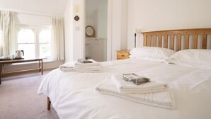 Une chambre d’hôtel avec un grand lit, une table de chevet, un miroir et une fenêtre avec des rideaux.