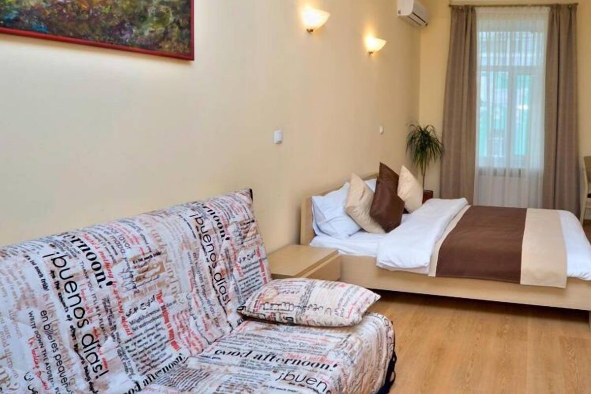 Una habitación de hotel con cama, sofá, una mesita y televisión.