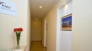 A hallway with a sign for 'kiev apartments', a vase with red flowers, and a framed picture on the wall. - Heart Kiev Apartments (Kyiv)