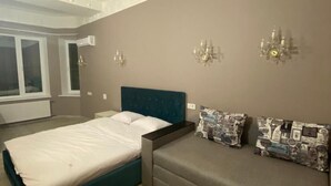 A bedroom with a large bed, a sofa, and a mirror. - Heart Kiev Apartments (Kyiv)