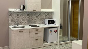 A compact kitchenette with a sink, microwave, and small refrigerator. - Heart Kiev Apartments (Kyiv)