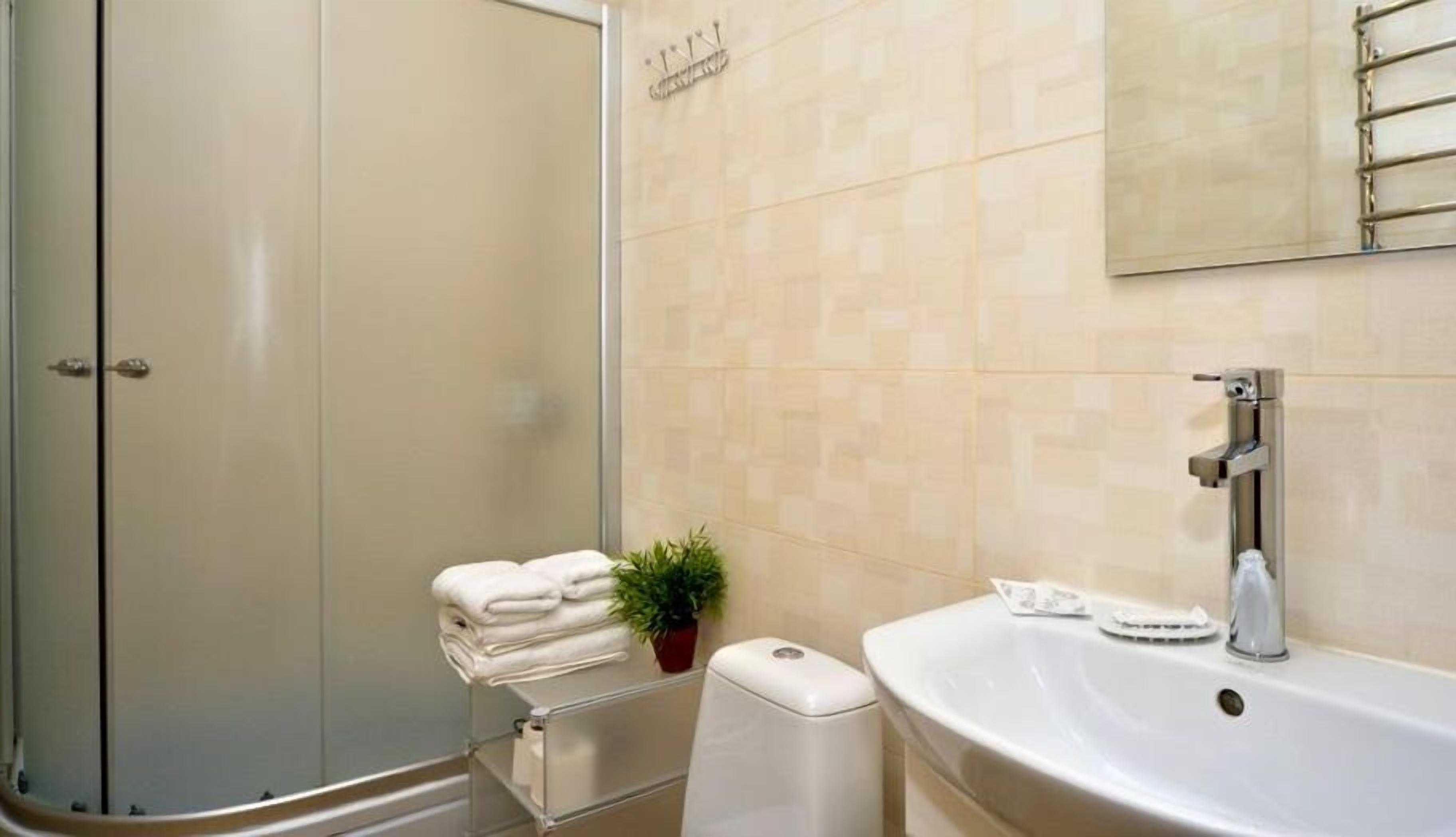 A bathroom with a shower, a sink, a toilet, and a towel rack.